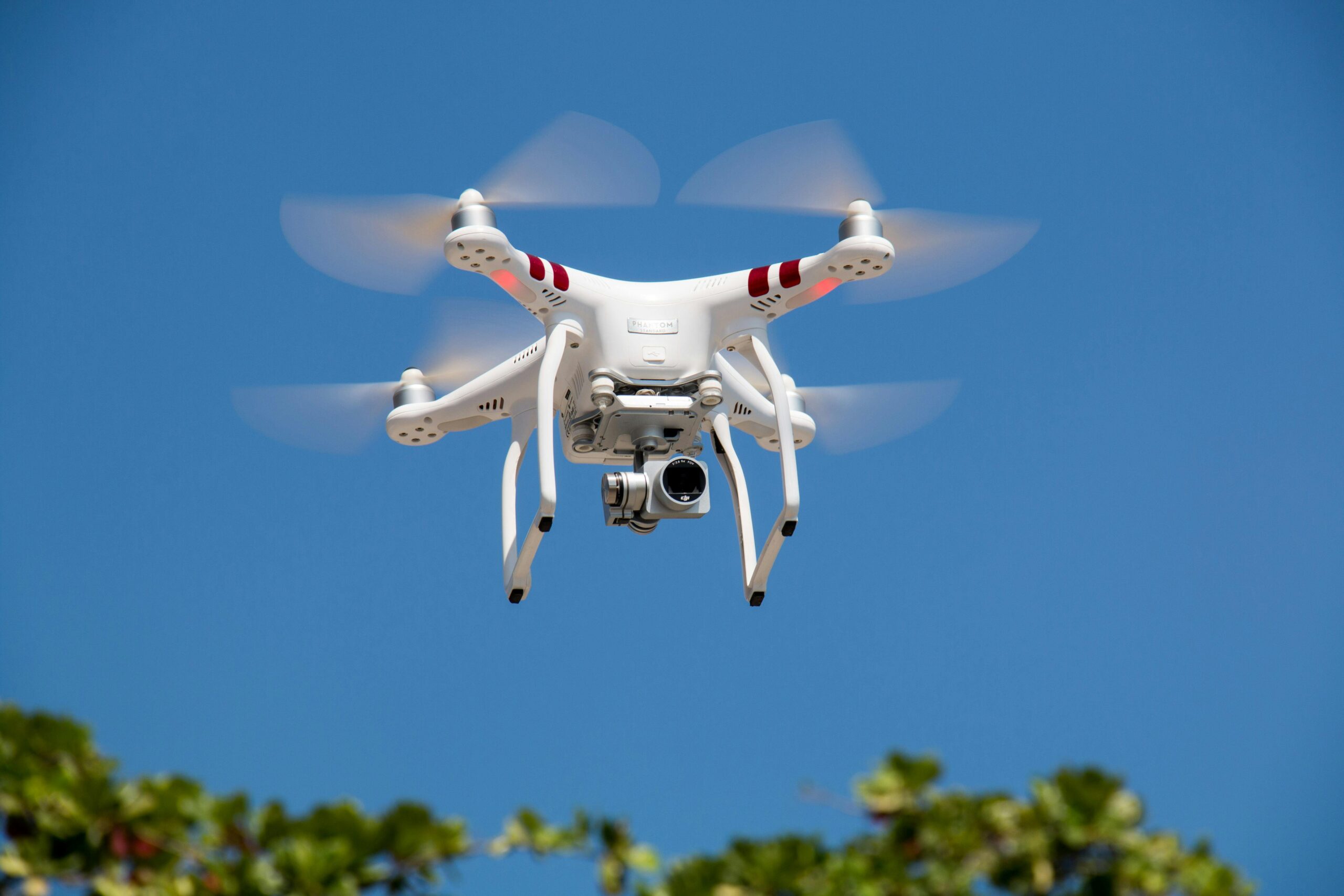 A white drone flying with camera against a clear blue sky in La Libertad.