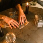 A fortune teller uses tarot cards and candles in a mystical indoor setting.